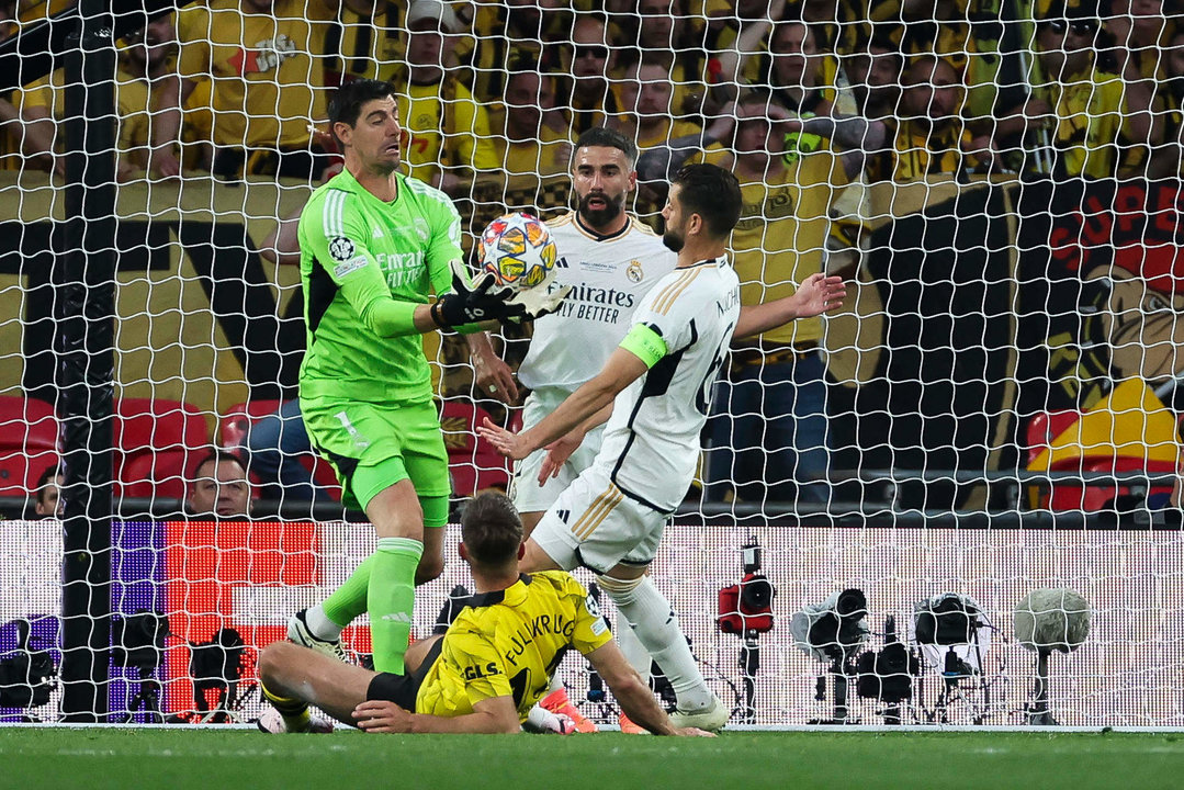 El guardameta belga del Real Madrid, Thibaut Courtois (i), captura el balón ante sus compañeros y el delantero del Borussia Dortmund, Niclas Fulkrug, durante el encuentro correspondiente a la final de la Liga de Campeones que Real Madrid y Borussia Dortmund disputaron en el estadio de Wembley, en Londres. EFE / Kiko Huesca.