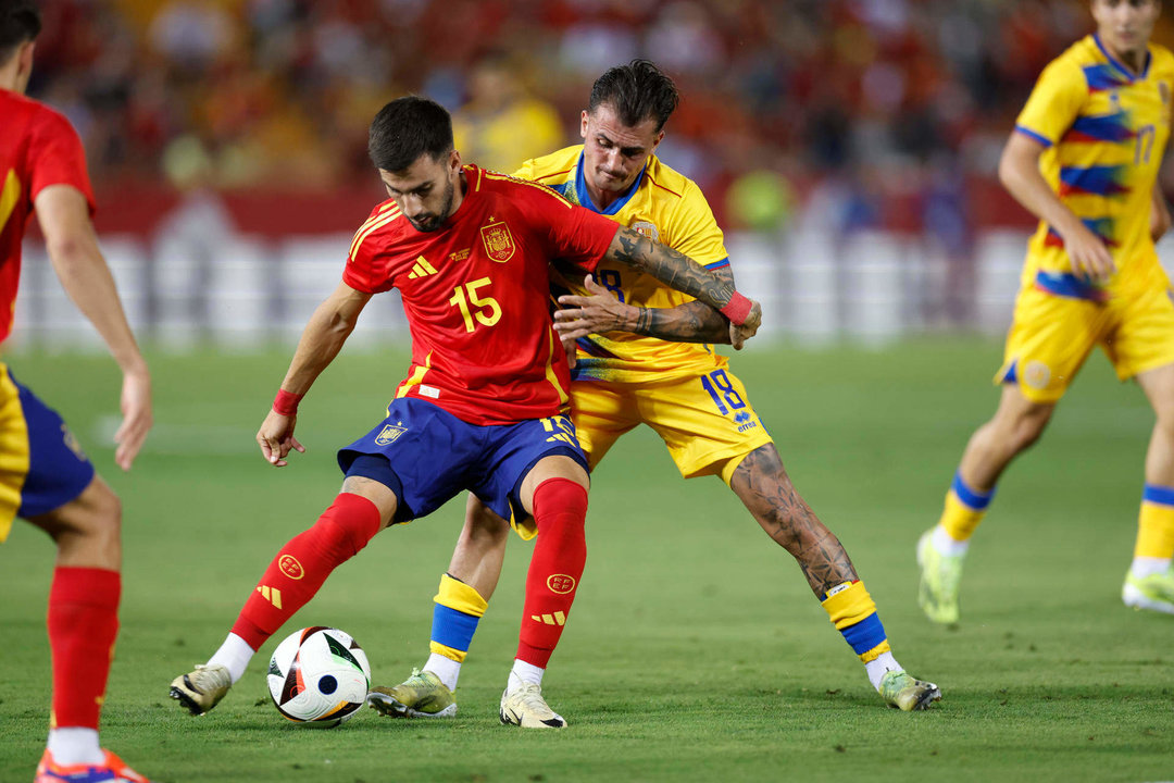 El centrocampista de la selección española de fútbol Álex Baena (i) protege un balón ante el andorrano Jesús Rubio, durante el partido amistoso que España y Andorra disputan este miércoles en el estadio Nuevo Vivero, en Badajoz. EFE/Julio Muñoz