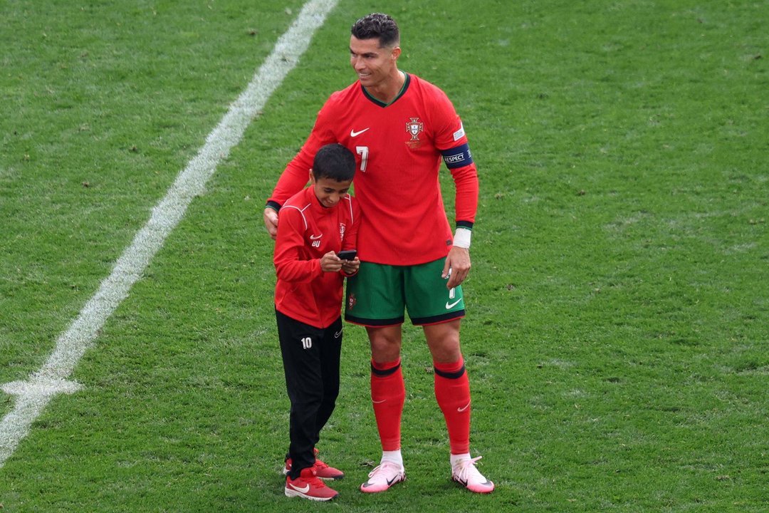 El jugador portugués Cristiano Ronaldo abraza a un niño en el campo durante el partido de fútbol del grupo F de la Eurocoà 2024 entre Turquía y Portugal, en Dortmund, Alemania, .EFE/EPA/CHRISTOPHER NEUNDORF